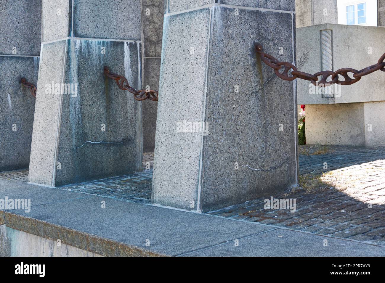 Closeup of concrete structures on the promenade by a harbour with copy space. Rusty chains hanging between stone pillars on a pier outside. A large barrier surrounding a bricked dock surface outdoors Stock Photo