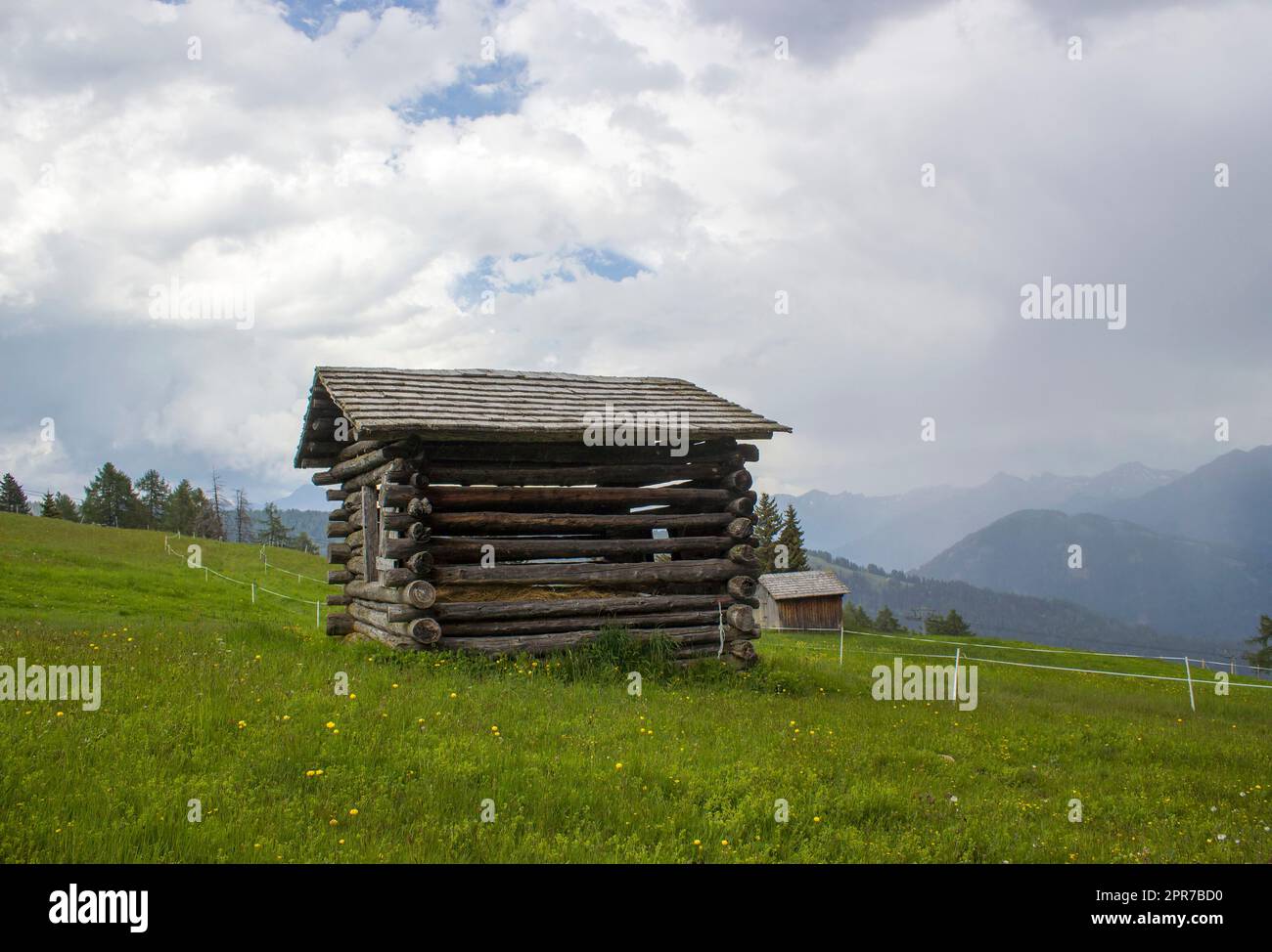 View of alpine landscape in summer with barn house surrounded by a green field Stock Photo