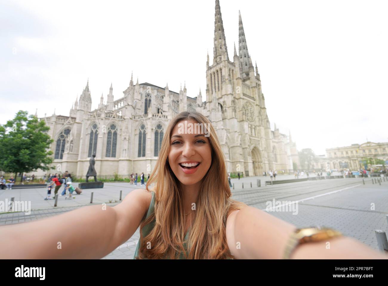 Woman in great mood takes selfie photo in front of Bordeaux Cathedral, France Stock Photo