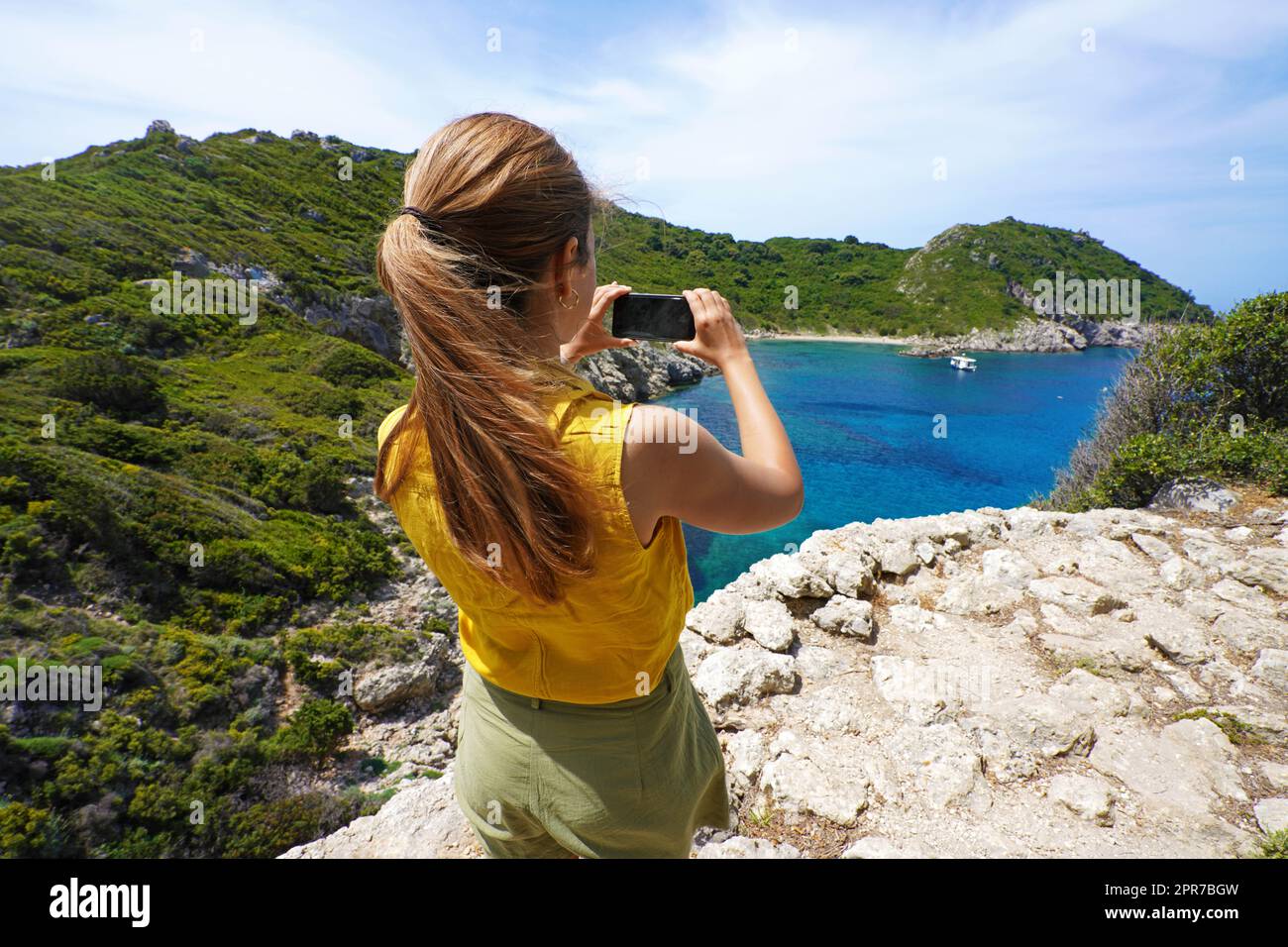 Young hiker explorer girl taking picture with smartphone of natural tropical panoramic view. Wide angle. Windy day. Stock Photo