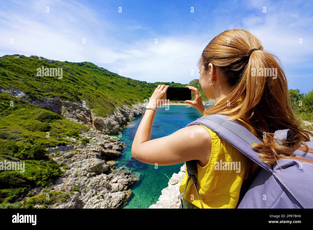 Young hiker girl taking photo with smartphone of natural tropical landscape. Wide angle. Stock Photo