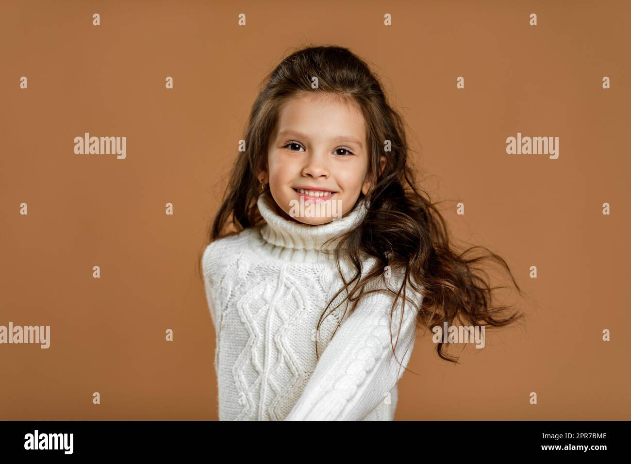 little girl in white sweater looking to camera Stock Photo
