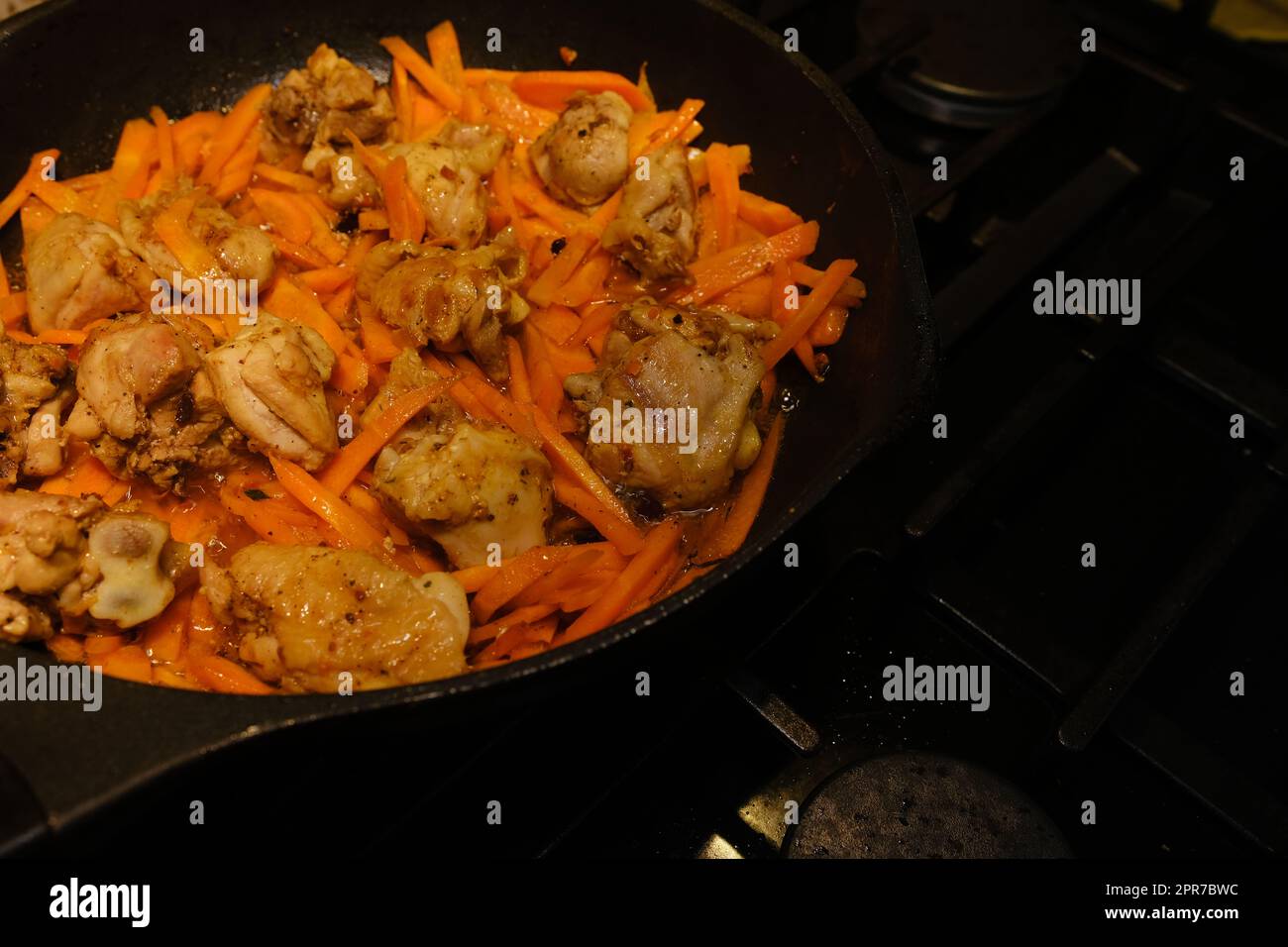 Homemade Korean Spicy chicken dish, frying chiken with carrot in a pan with sunflower oil. Stock Photo