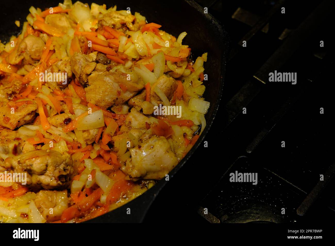 Homemade Korean Spicy chicken dish, frying chiken with carrot in a pan with sunflower oil. Stock Photo
