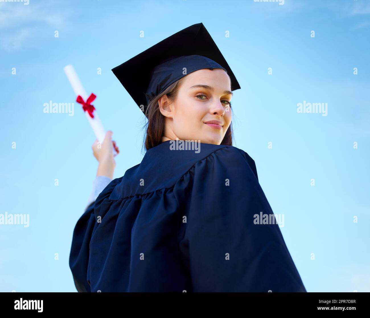 All my efforts paid off in a big way. Portrait of a young woman cheering with her diploma on graduation day. Stock Photo