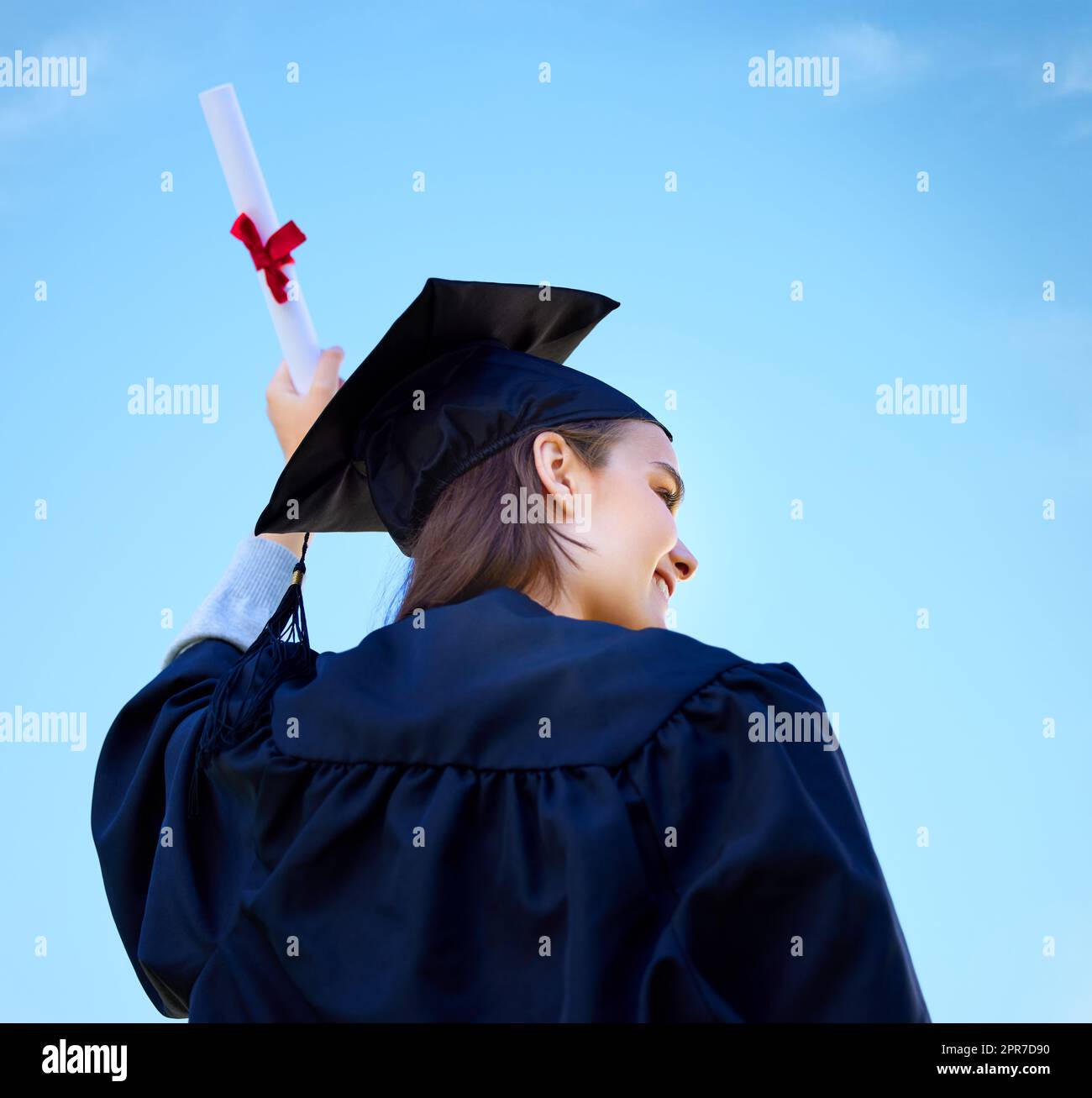 Set sail towards your dreams. Low angle shot of a young woman cheering with her diploma on graduation day. Stock Photo