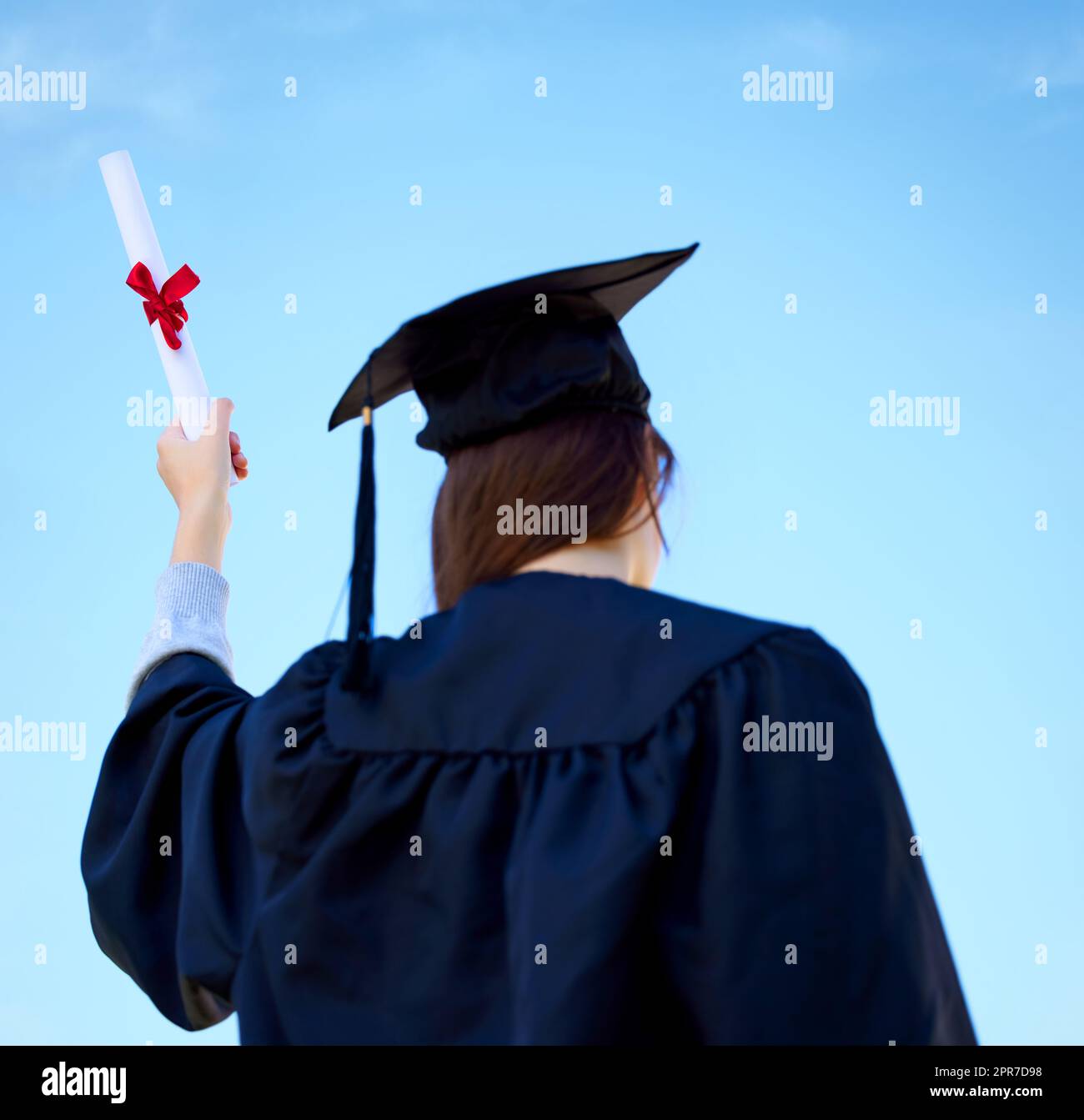 This is the beginning of many more achievements for me. Low angle shot of a young woman cheering with her diploma on graduation day. Stock Photo