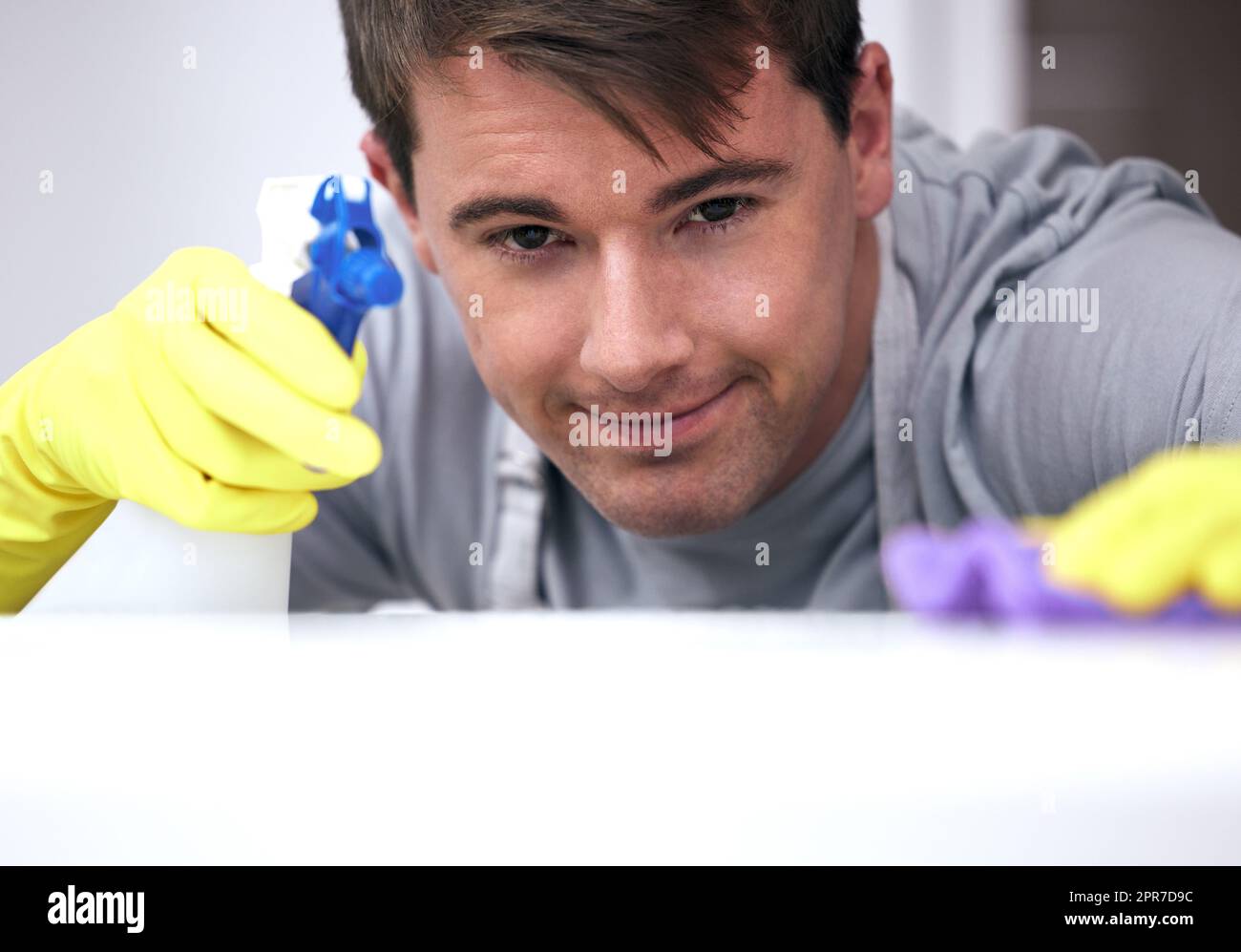 Lets take a closer look. a young man cleaning a surface at home Stock