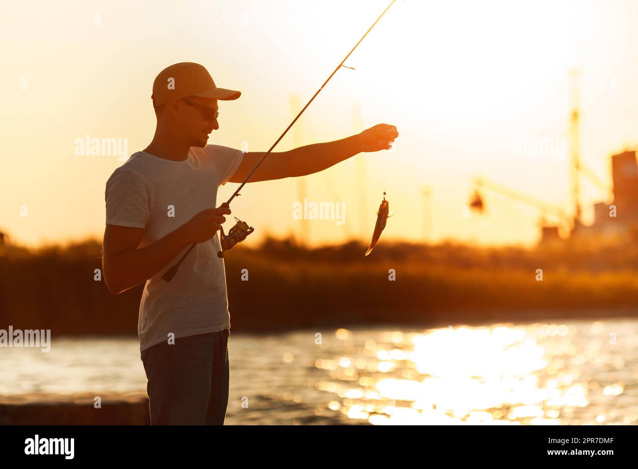 Young man fishing at sea Stock Photo - Alamy