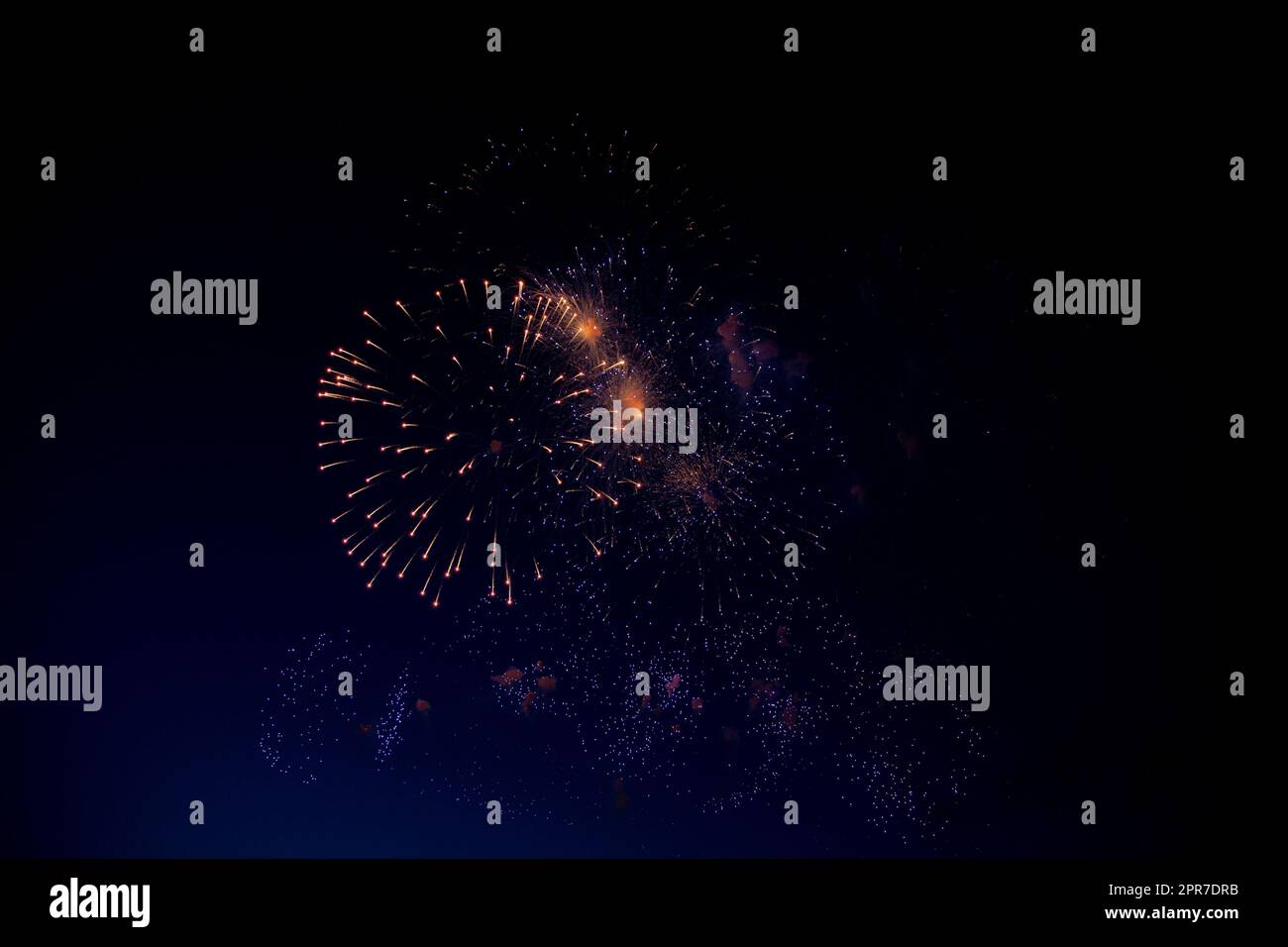 Bright orange fireworks and lots of blue and purple sparks on the background of the night sky Stock Photo
