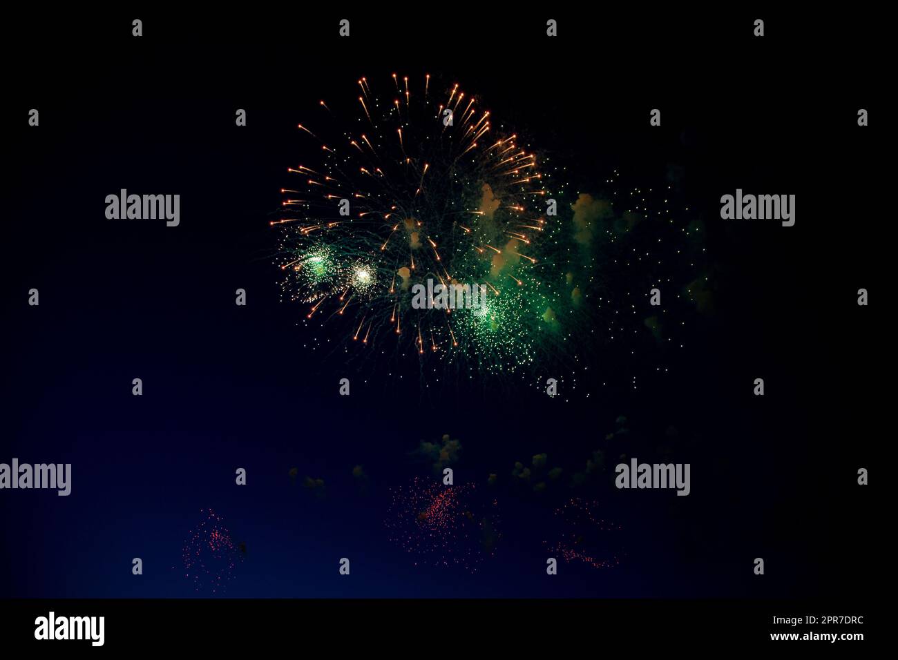 Bright orange fireworks and lots of green sparks on the background of the night sky Stock Photo
