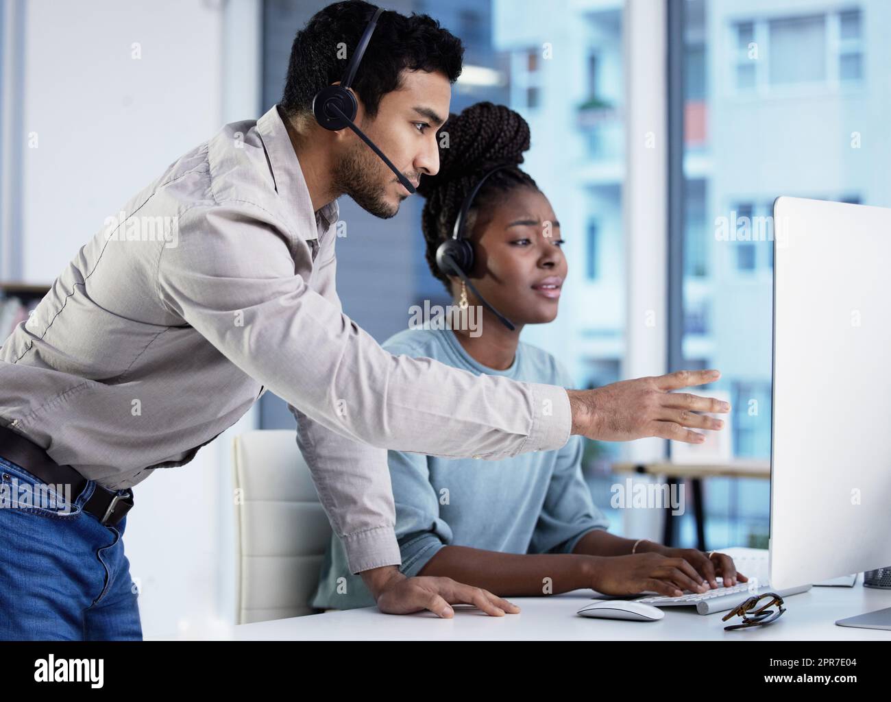 Dont panic, take your time. two young customer service agents having a  discussion in the office and using a computer Stock Photo - Alamy