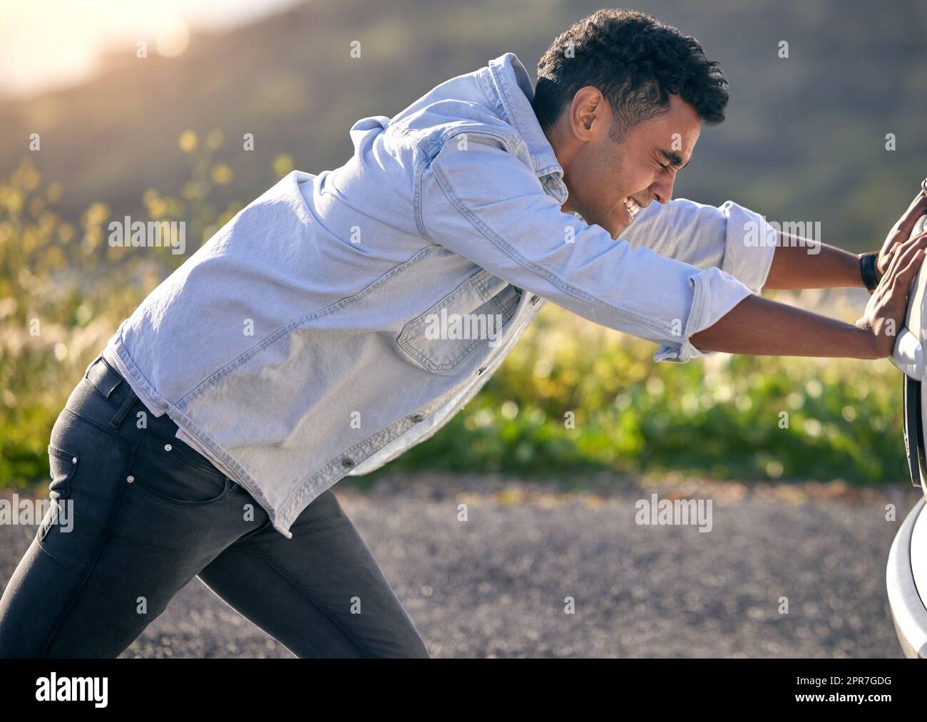 Can I push start her. Cropped shot of a handdsome young man pushing his car after suffering a vehicle breakdown. Stock Photo