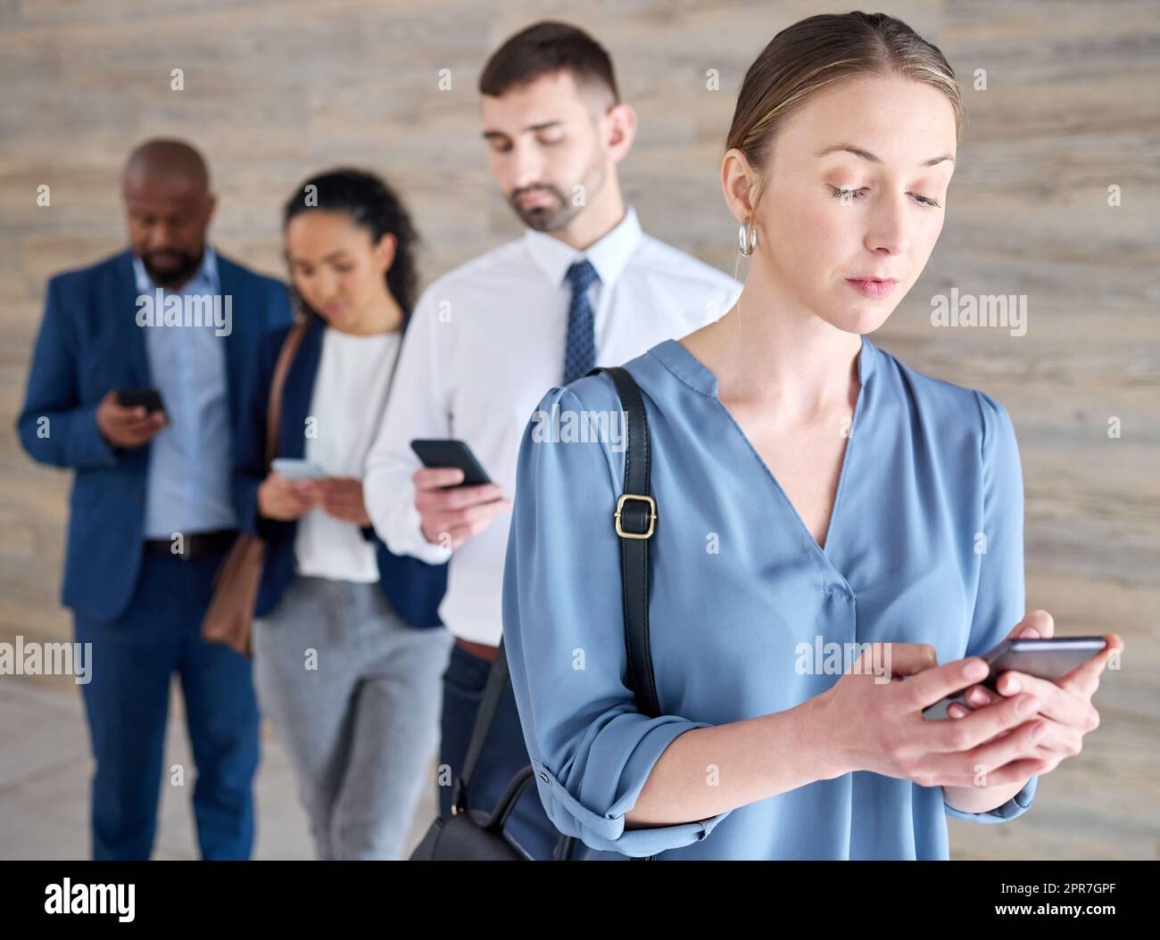 I can network on social media too. Shot of a mature businesswoman using a phone while waiting in line at an office. Stock Photo