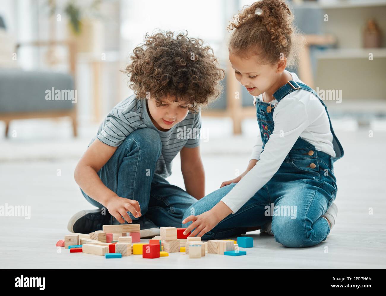 What shape do you want to make. two siblings playing with building blocks. Stock Photo