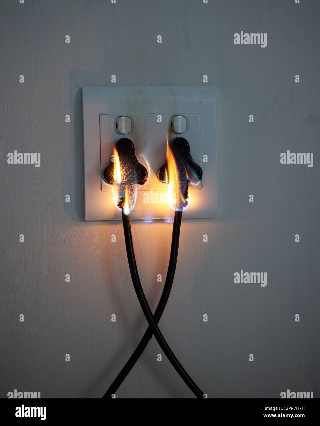 Are you covered. two plugs in a wall socket catching fire Stock Photo