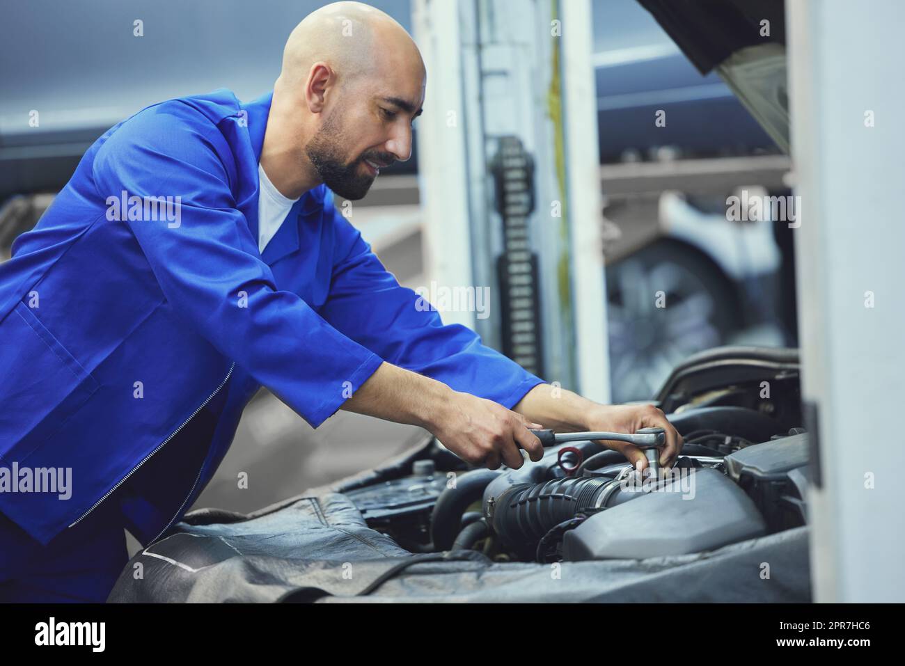 Hes an expert when it comes to engines. a handsome young male mechanic working on the engine of a car during a service. Stock Photo