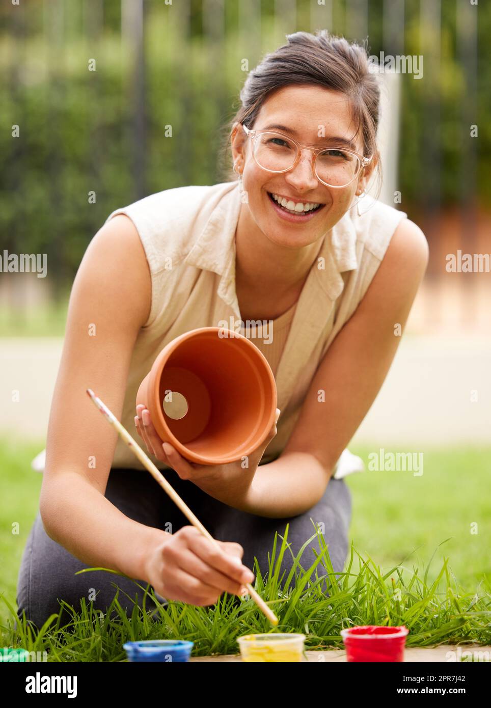 You cant use up creativity. The more you use, the more you have. s young woman painting a pot in the garden at home. Stock Photo