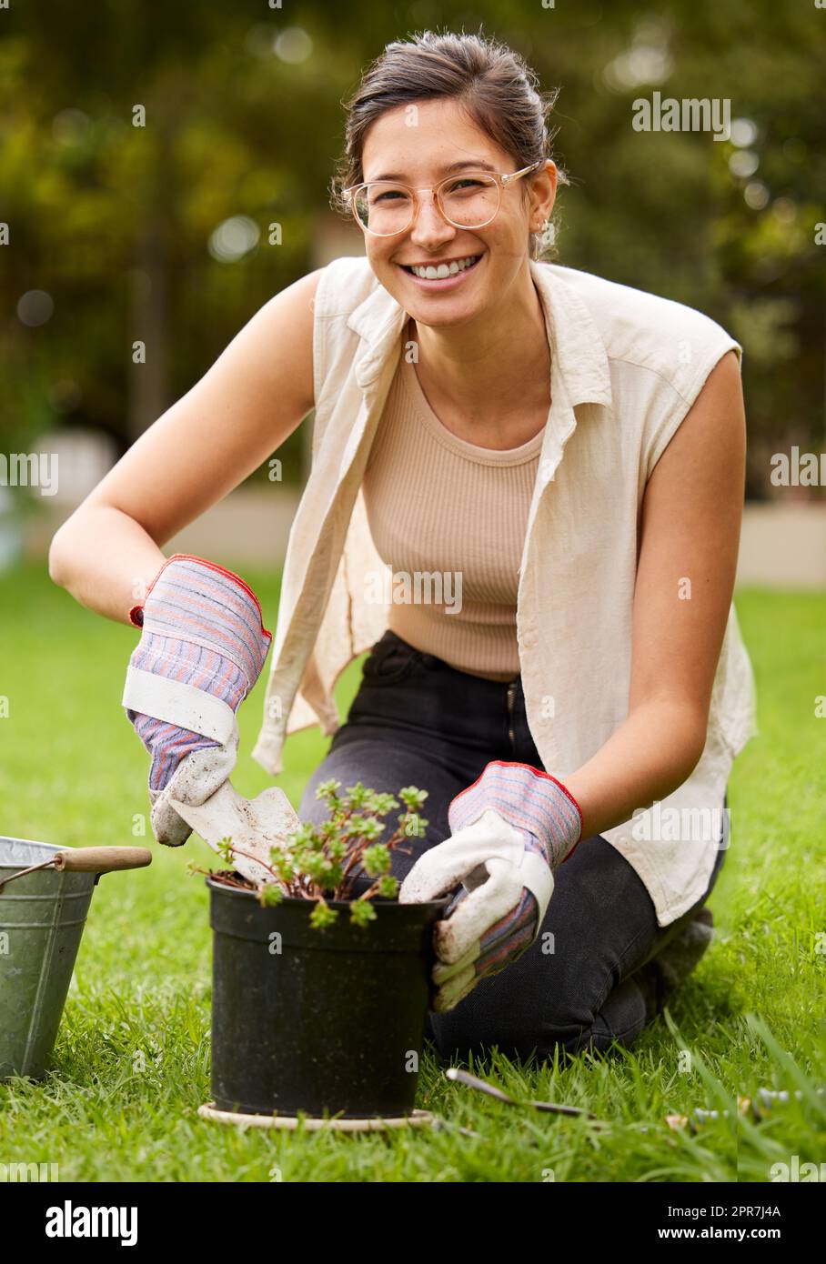A smile for sustenance. Portrait of a smiling woman kneeling while doing some gardening in the backyard. Stock Photo