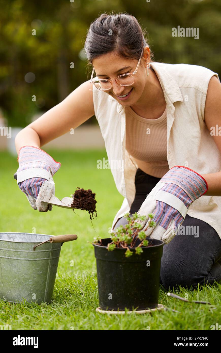 Paved with more than good intentions. an attractive young woman digging with a trowel while doing some gardening at home. Stock Photo