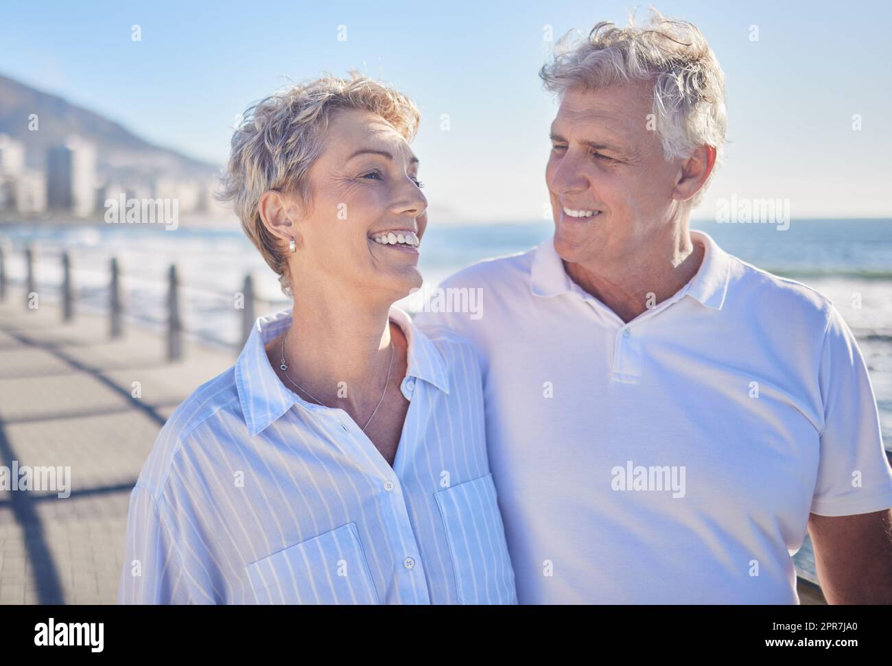 A happy mature caucasian couple enjoying fresh air on vacation at the beach. Smiling retired couple getting a cardio workout while walking outside Stock Photo