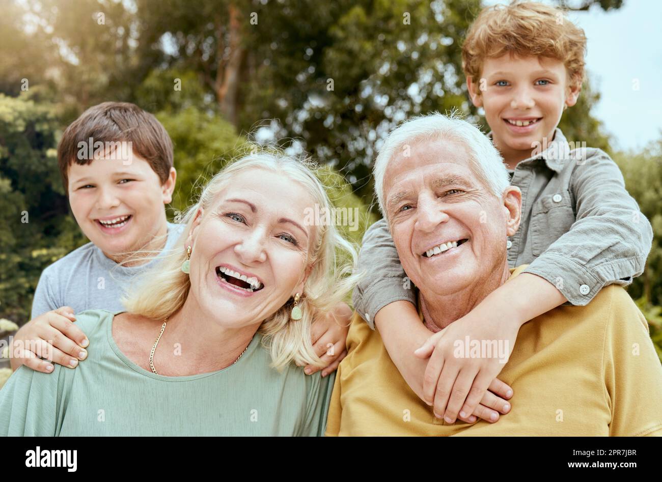 Portrait of two little boys spending time with their grandparents outside . Mature caucasian couple babysitting their grandchildren on the weekend and having fun in the backyard Stock Photo