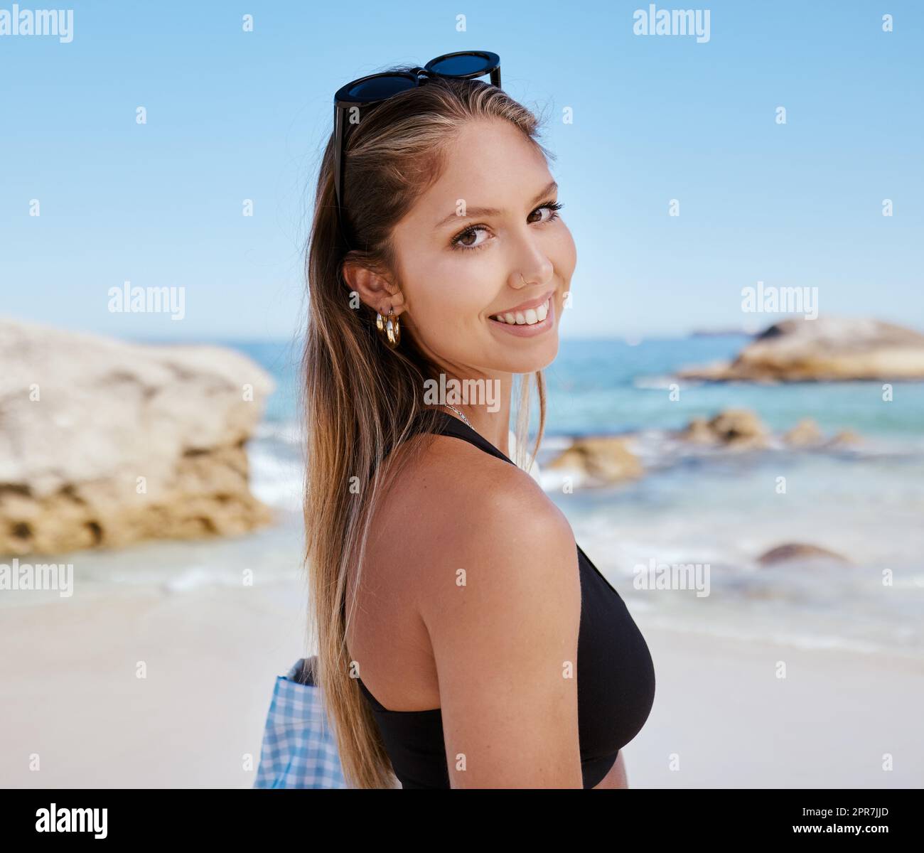 One beautiful young caucasian woman relaxing on the beach. Enjoying a summer vacation or holiday outdoors during summer. Taking time off and getting away from it all. Spending the day alone outside Stock Photo