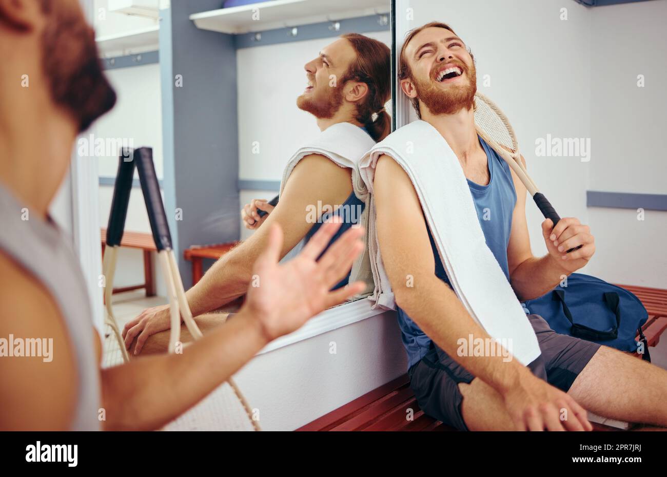 Cheerful squash players laughing and talking. Two friends taking a break from their match to relax. Happy friends bonding in the gym locker room. Two men bonding before playing a game of squash Stock Photo