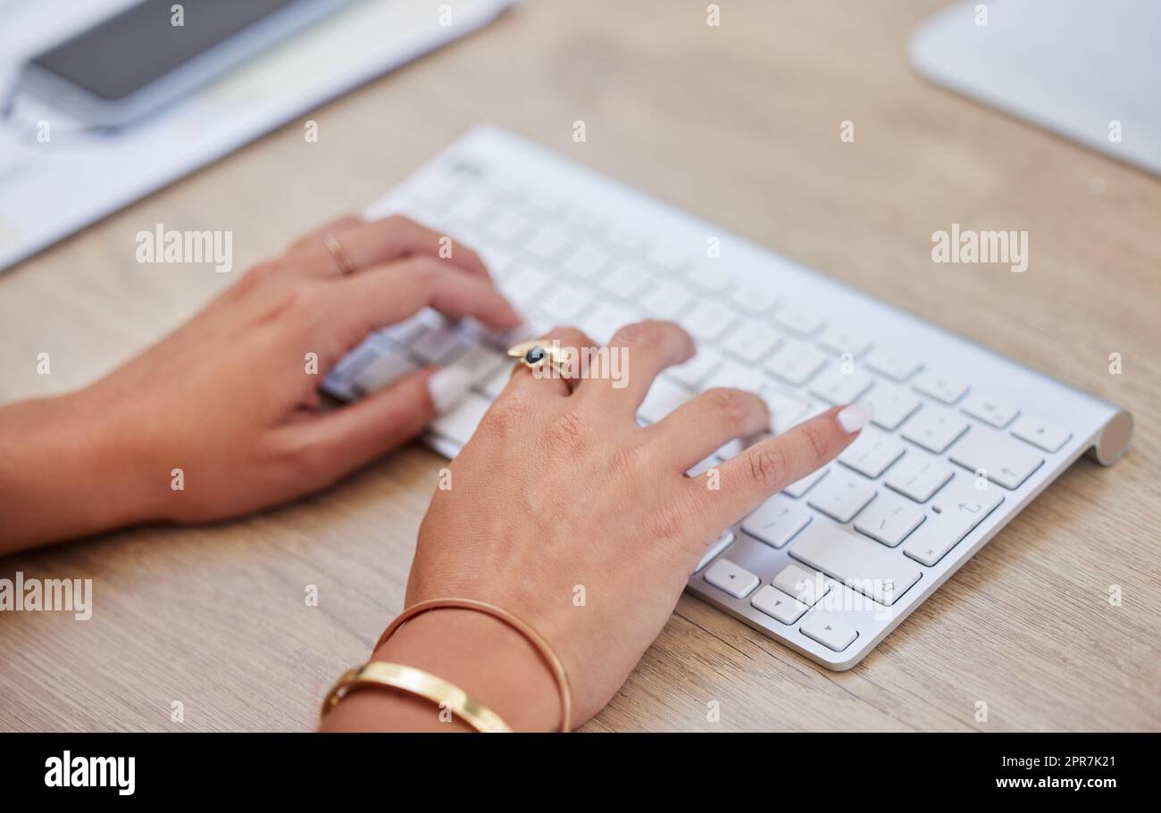 Closeup of one business womans hands and fingers typing on desktop computer keyboard at a table in an office. One female only sending emails while doing research and planning online for her startup Stock Photo