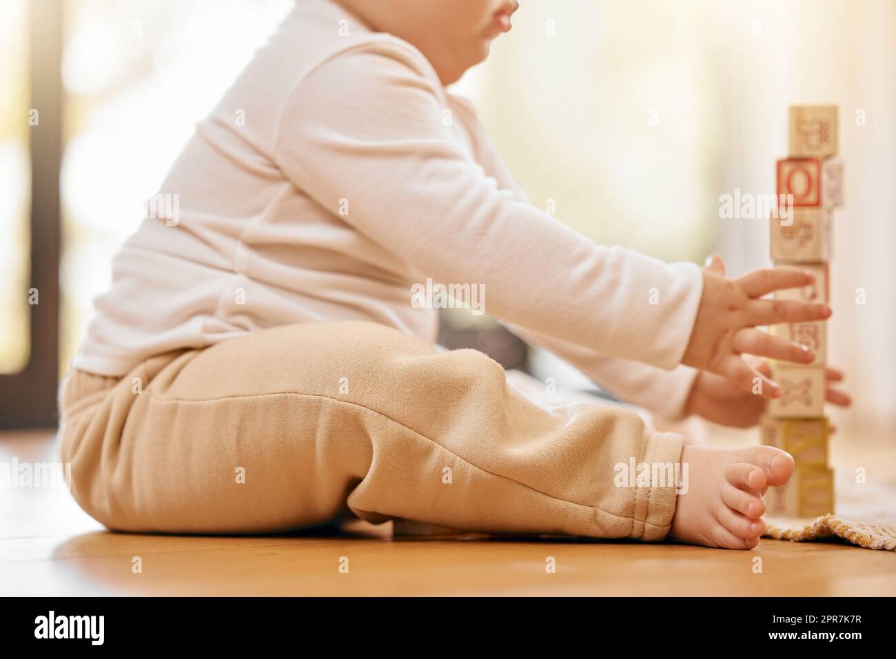 In the hearts of their mothers, they are still little. a unrecognizable baby playing with blocks at home. Stock Photo