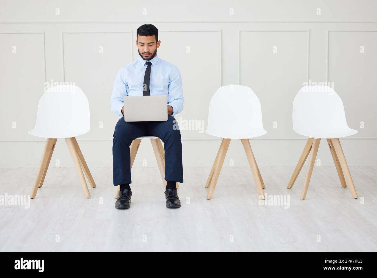 Fullbody asian businessman waiting for interview and using laptop. Applicant sitting alone, browsing internet on technology. Professional candidate in line for job opening, vacancy, office opportunity Stock Photo