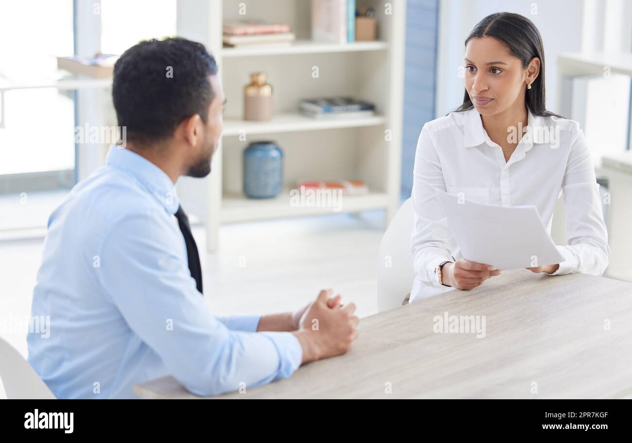 Mixed race hiring manger in interview with businessman. CEO with resume and cv of candidate looking for job opening, vacancy, office opportunity. Applicant sitting and explaining experience to hr boss Stock Photo