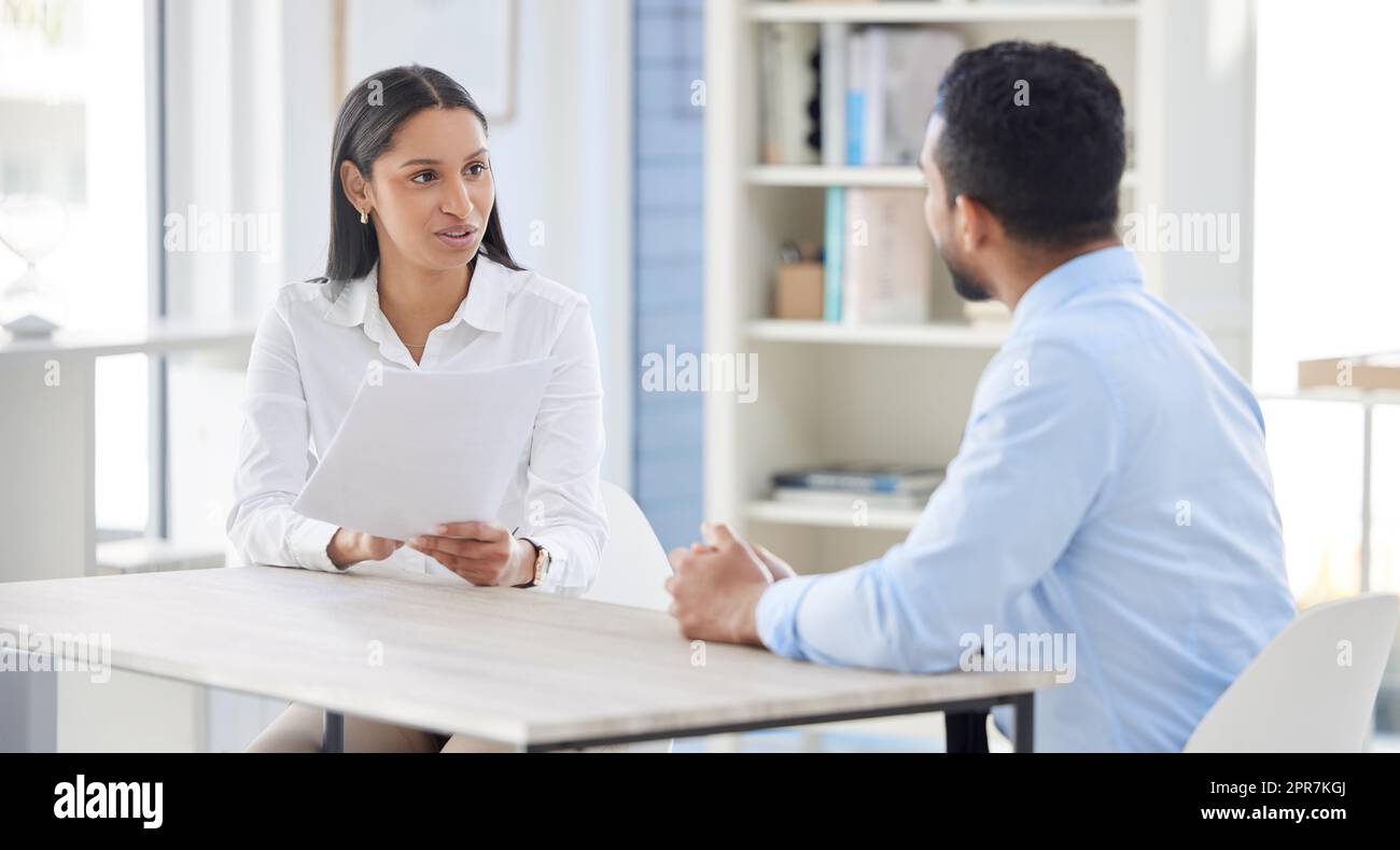 Mixed race hiring manger in interview with businessman. CEO with resume and cv of candidate looking for job opening, vacancy, office opportunity. Applicant sitting and explaining experience to hr boss Stock Photo
