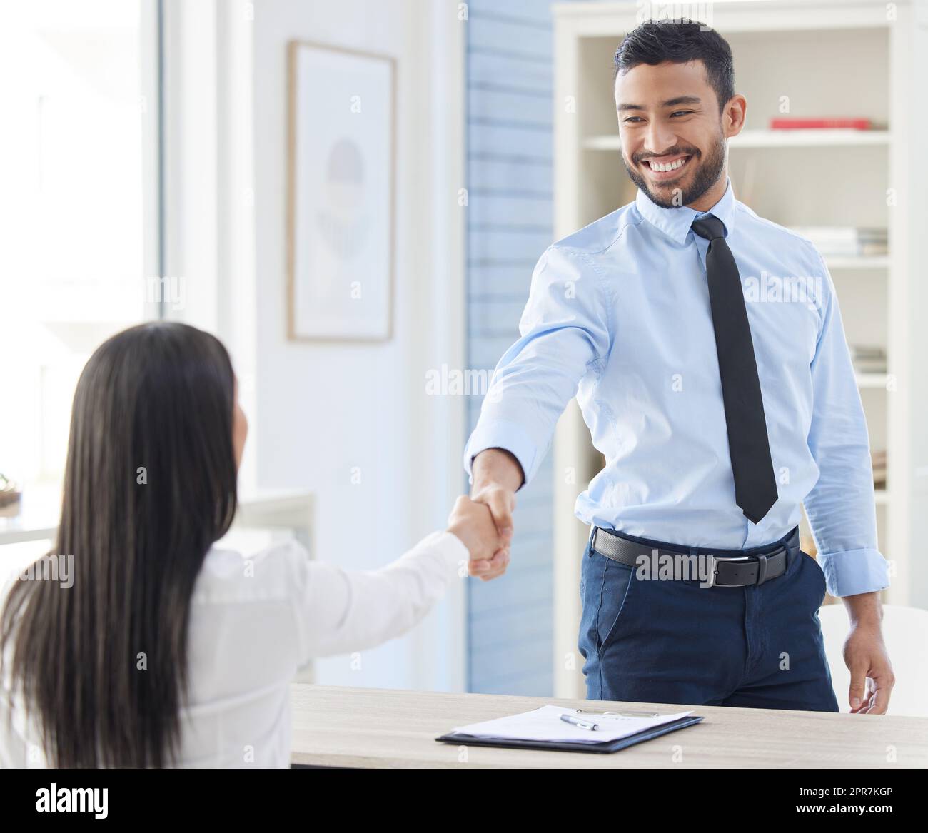 Two mixed race businesspeople in handshake after signing contract in interview. Asian applicant meeting CEO and hiring manger. Candidate hired for job opening, vacancy, office opportunity, promotion Stock Photo