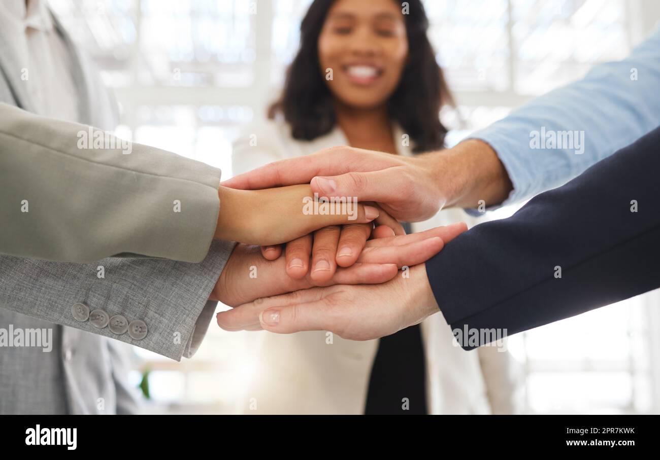 Group of businesspeople stacking their hands together in an office at work. Business professionals having fun standing with their hands piled for motivation during a meeting Stock Photo