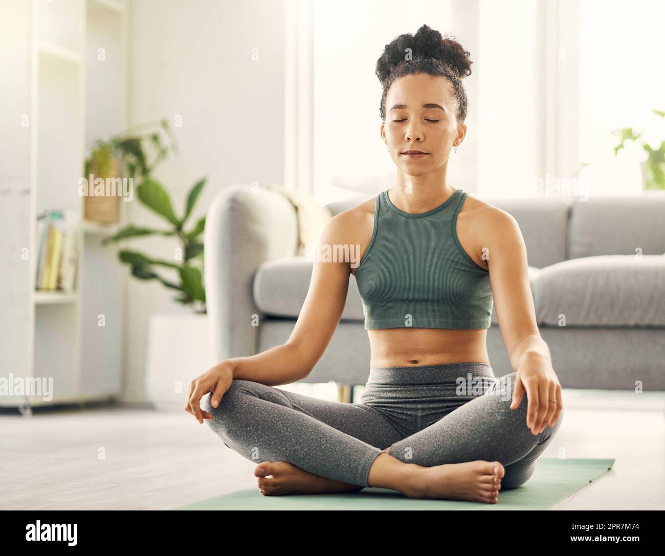 If you dont meditate then youre missing out on peace. a young woman practising yoga in her living room. Stock Photo