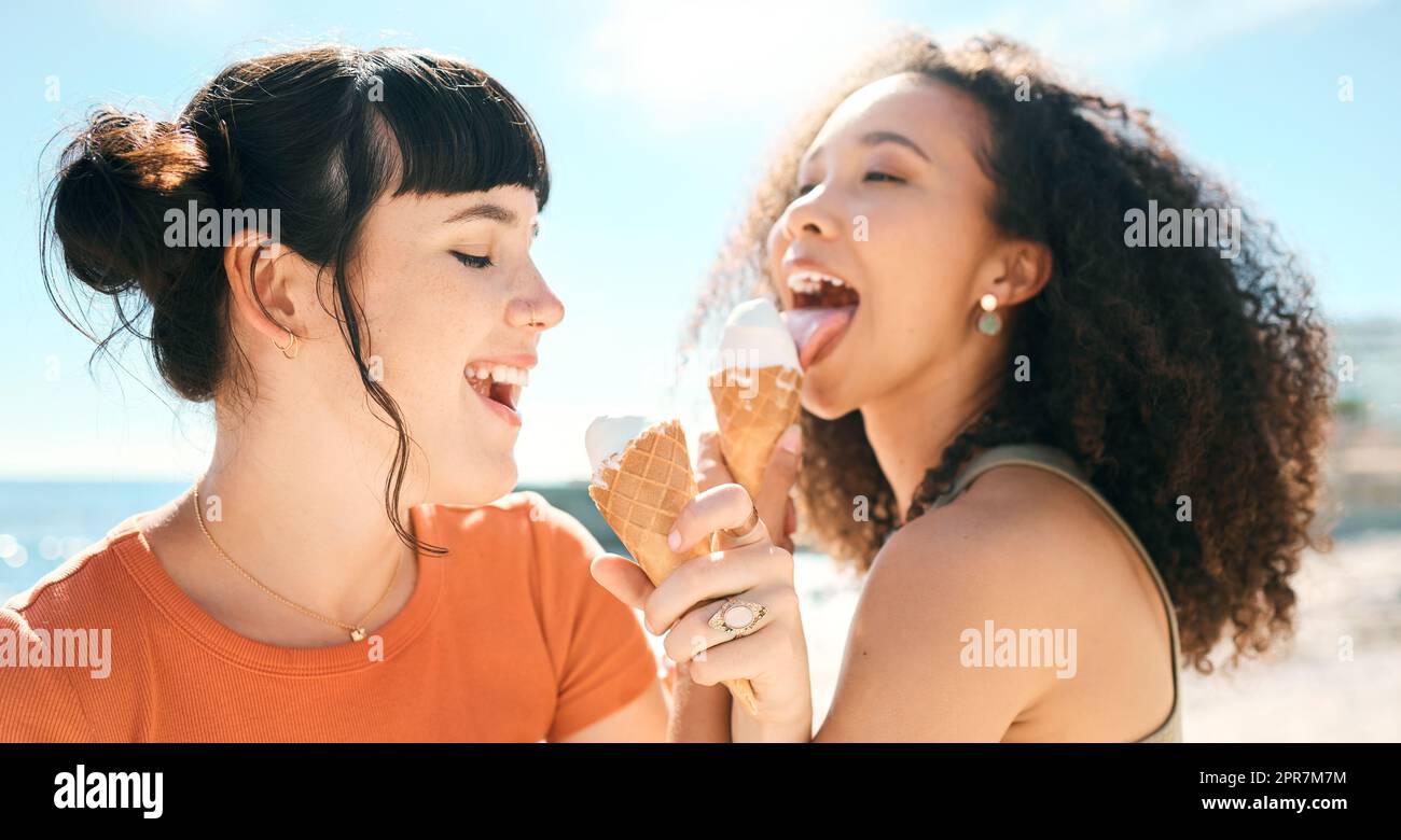 The season of sunshine and smiles. two attractive young girlfriends enjoying ice creams on the beach. Stock Photo