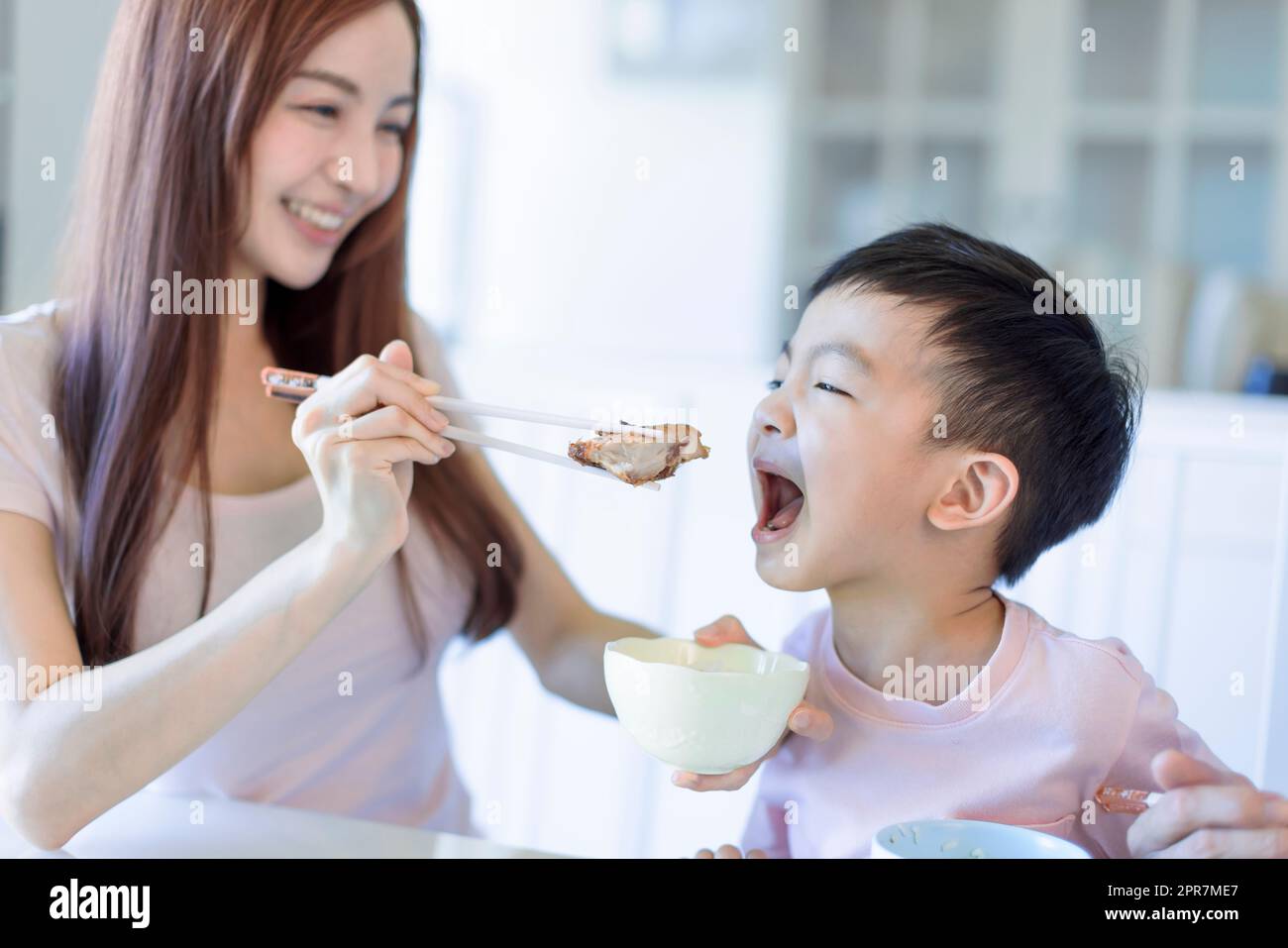 little boy  enjoy eating food with  mother. Happy Asian  family having dinner at home Stock Photo