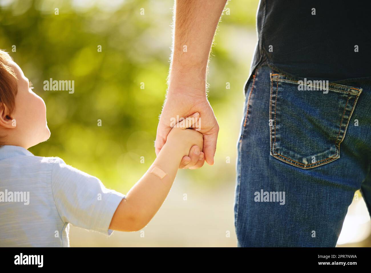 Hell always have a hand to hold. Shot of a little boy holding his dads hand on a walk in the park. Stock Photo