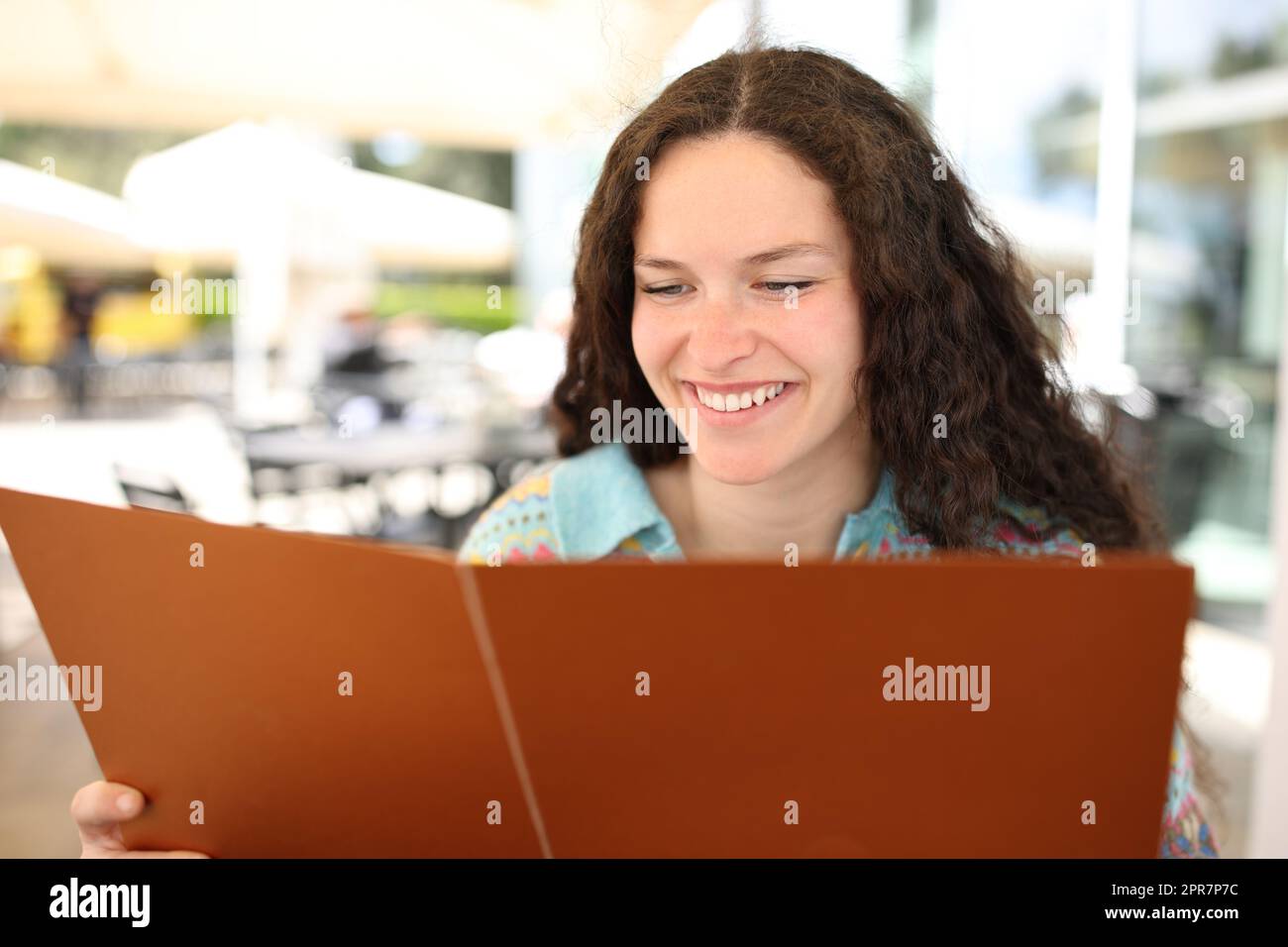 Happy woman reading menu card in a bar Stock Photo