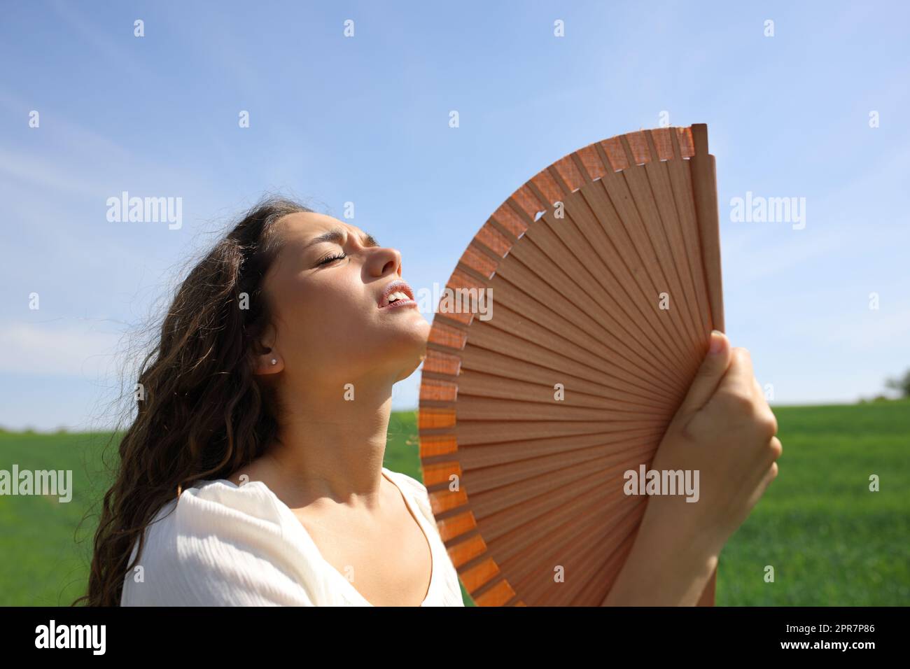 Stressed woman fanning suffering heat stroke in a field Stock Photo