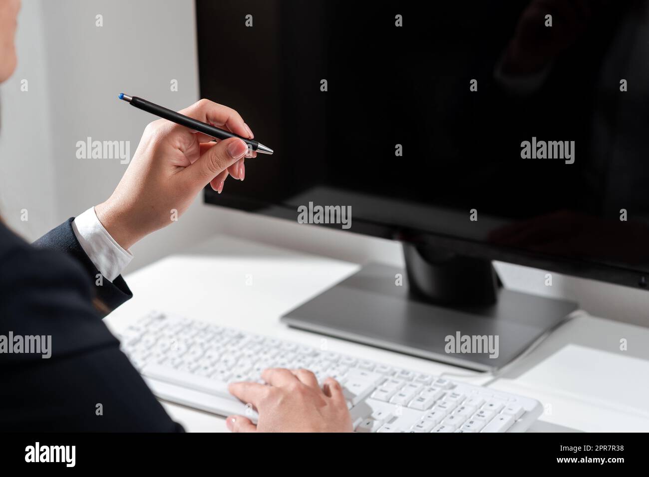 Businesswoman Typing Recent Updates On Lap Top Keyboard On Desk And Pointing Important Ideas With Pen. Woman In Office Writing Late Messages On Computer. Stock Photo