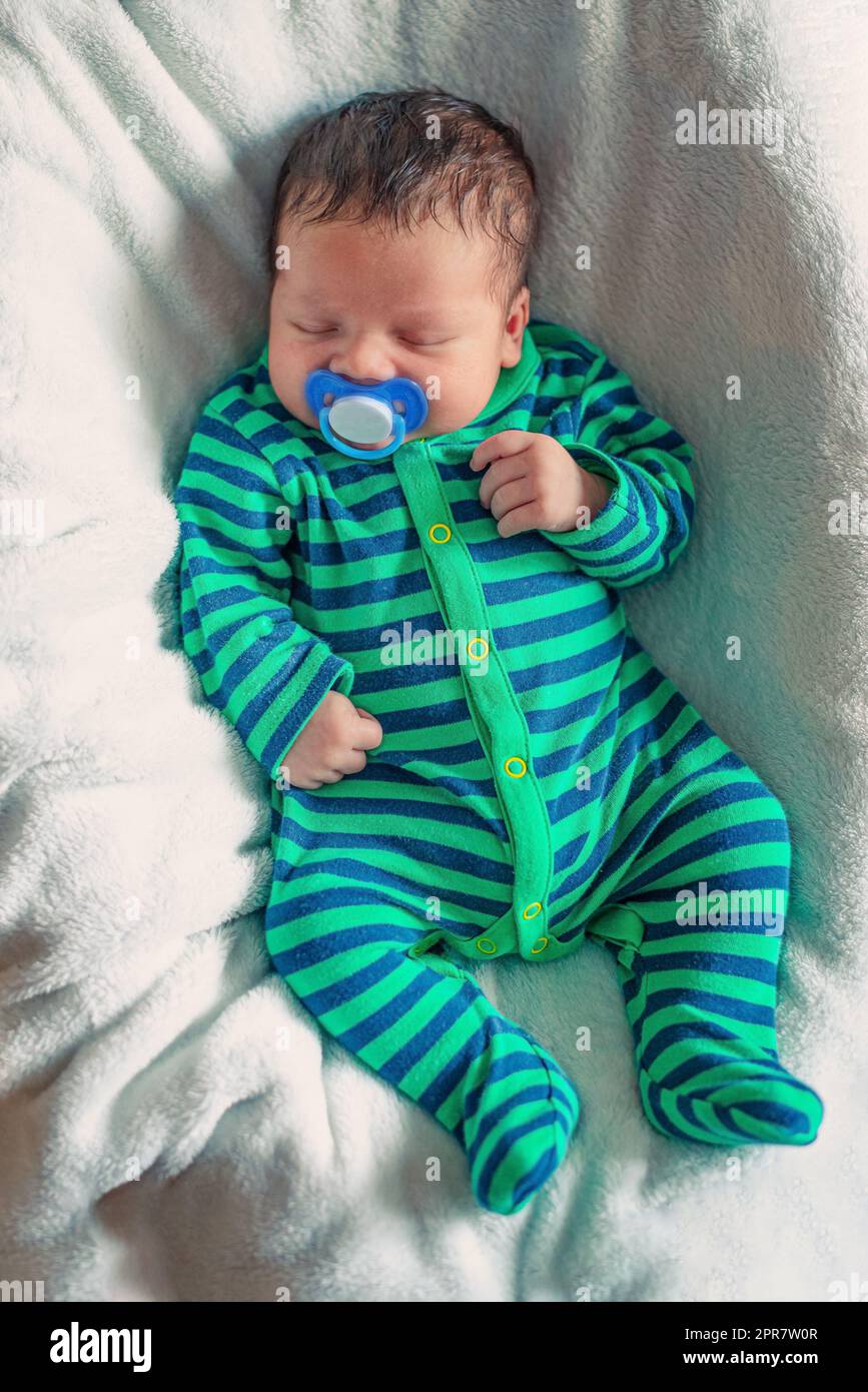 newborn baby sleeping on a white blanket with a pacifier in his mouth