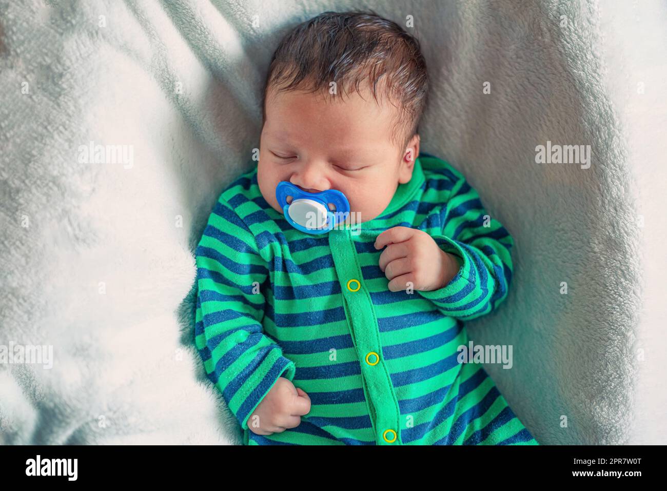 portrait of a newborn baby boy who sleeps with a pacifier in his mouth