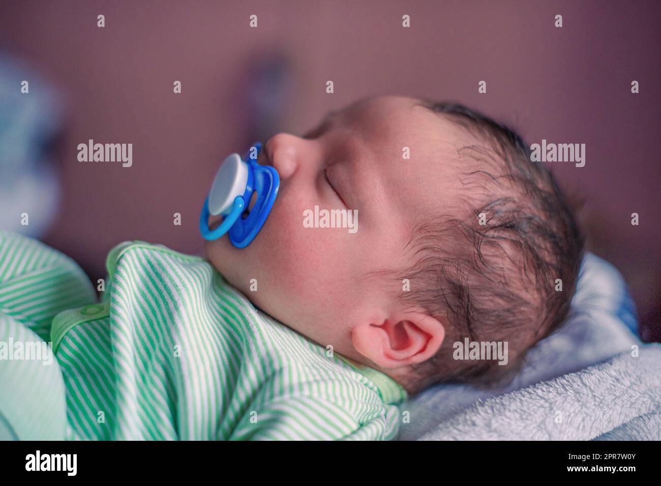 Face profile portrait of a sleeping newborn baby with a pacifier in his mouth Stock Photo