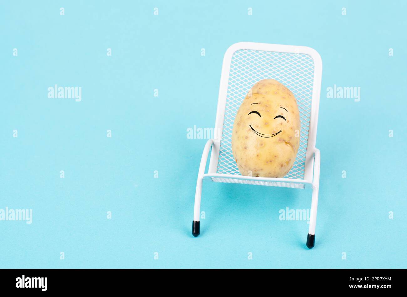 Potato with a funny face is sitting in lounge chairs, happy holiday, greeting card Stock Photo