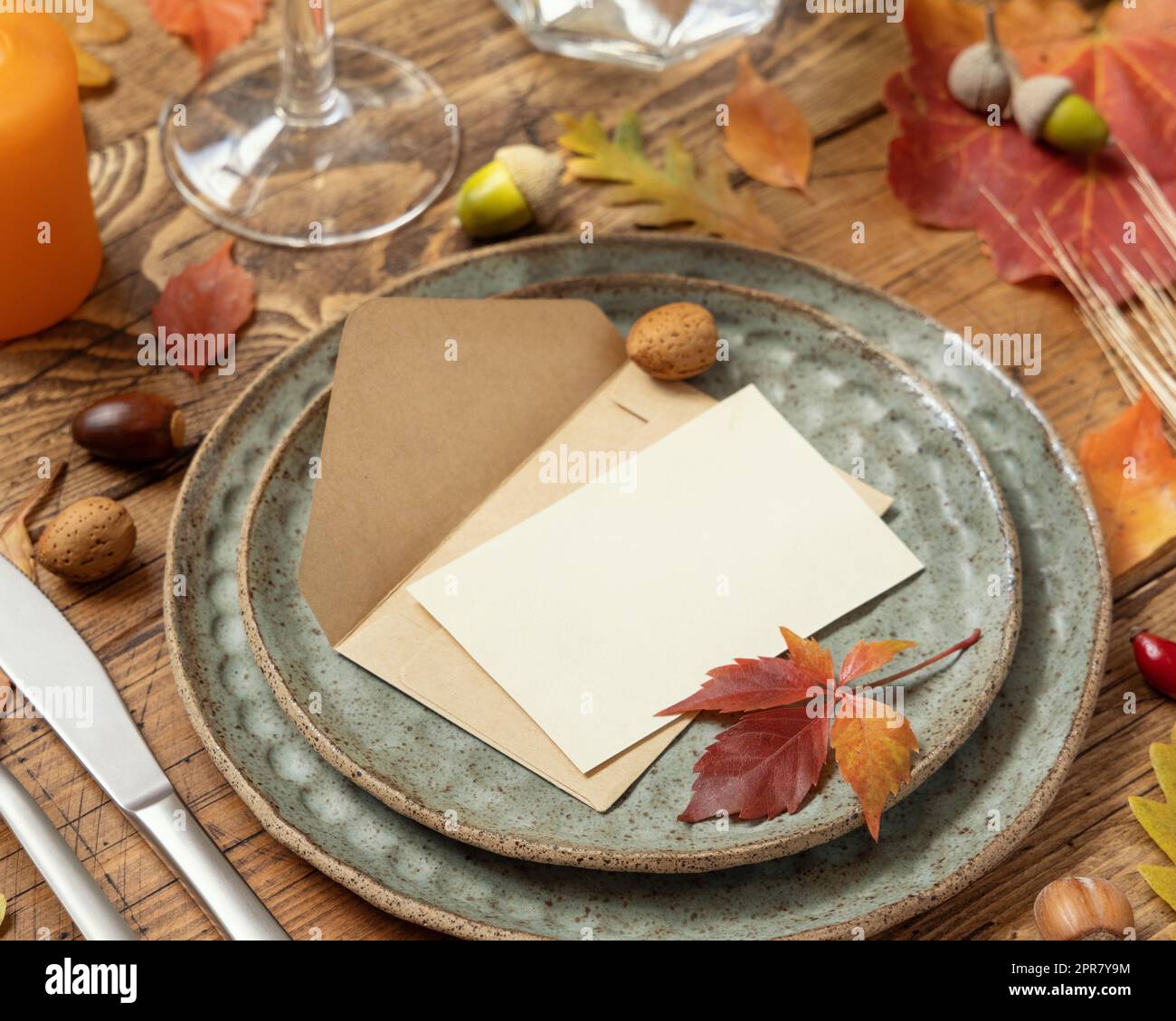 Autumn table setting with place card and envelope between leaves and berries close up, mockup Stock Photo