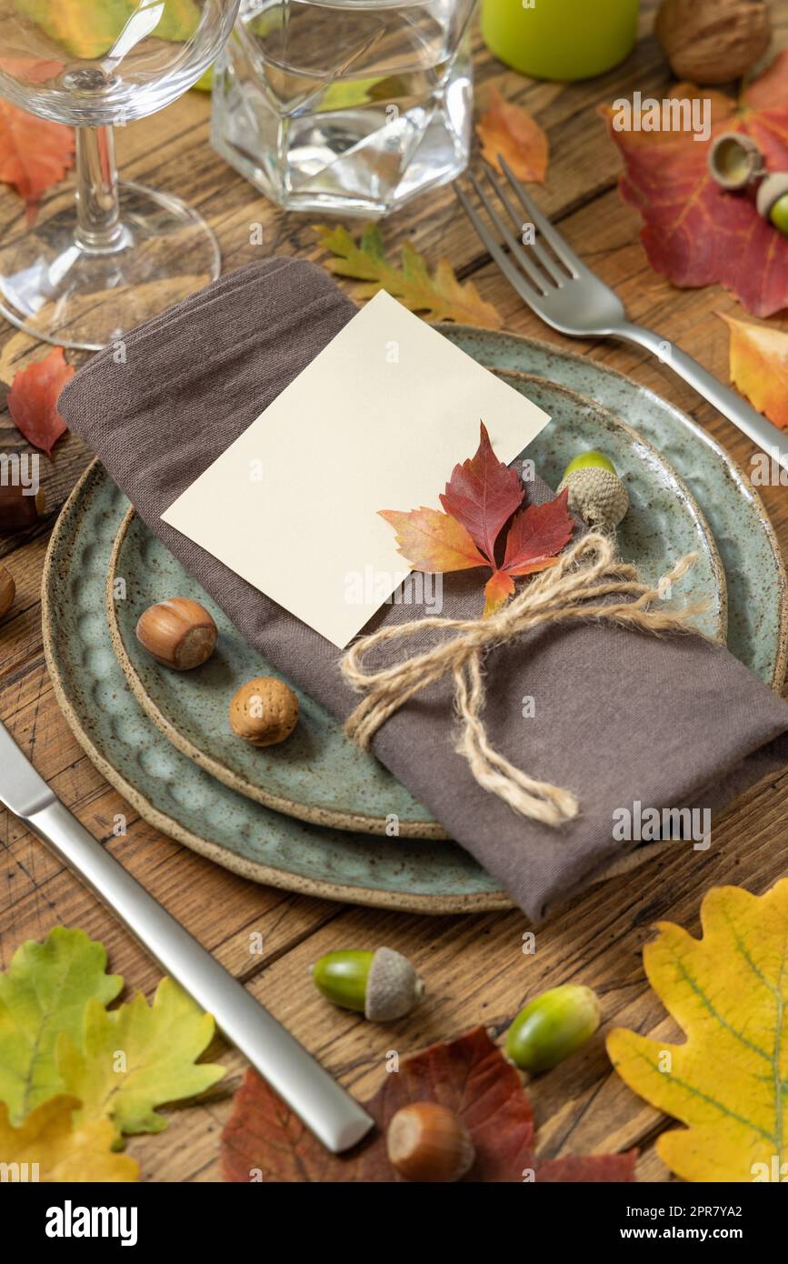 Autumn rustic table setting with blank place card between colorful leaves and berries close up, mockup Stock Photo