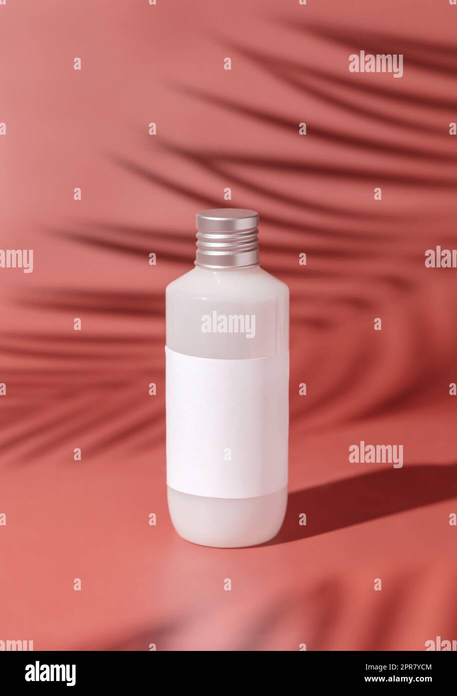 Plastic bottle with blank label on pink, Palm leaf hard shadows. Mockup Stock Photo