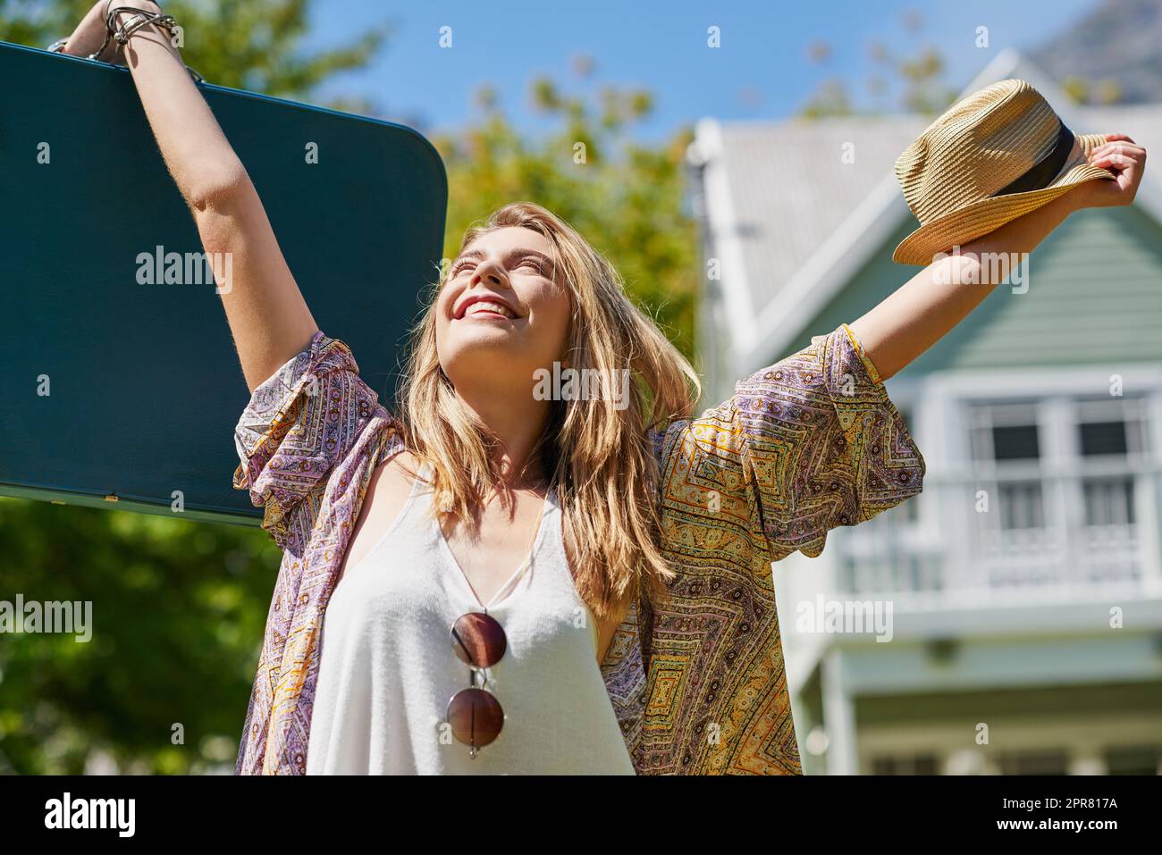 My life is mine and Im living it. Shot of an attractive young woman standing outside her home on a summers day and cheering. Stock Photo
